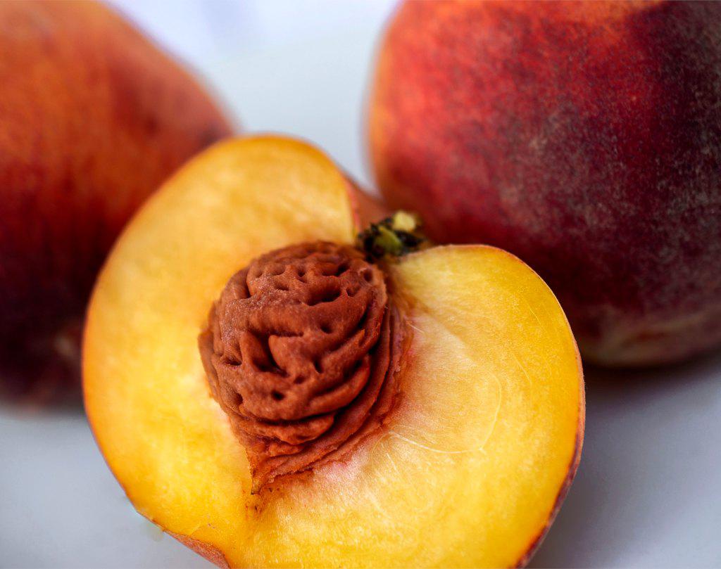 A sliced peach shows its kernel and healthy flesh.