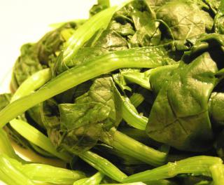 A pile of steamed spinach leaves on a plate.