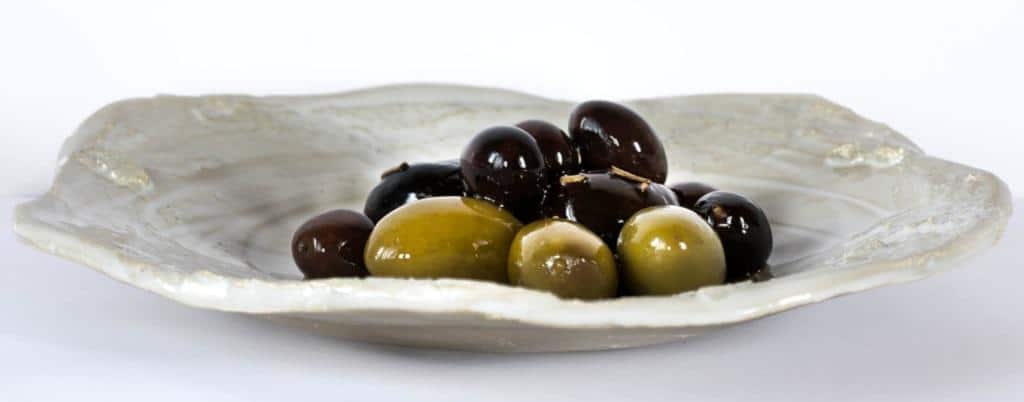 Green and black olives prepared for appetizers on a small white dish.