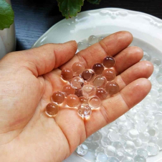 A hand has scooped up hydrogel beads from a plate.