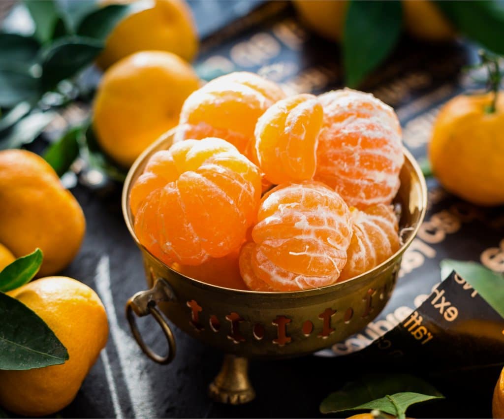 Peeled clementines or mandarin oranges in a brass bowl.