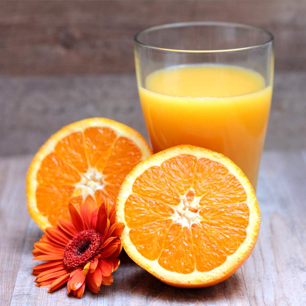 Two orange halves with a glass of orange juice and an orange gerbera flower.