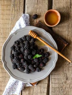 Blackberries in a plate with a dollup of honey.