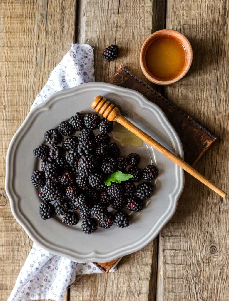 Blackberries in a plate with a dollup of honey.