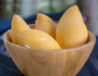 Four mangoes in a wood bowl