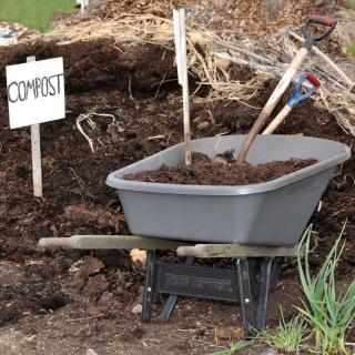 Pile of compost with sign and wheelbarrow