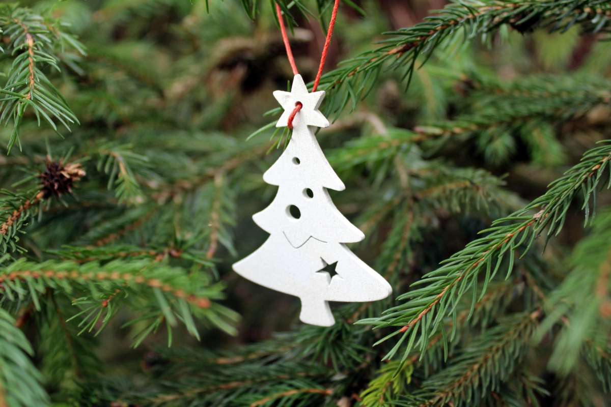 A Christmas tree ornament shaped like a Christmas tree on a spruce Christmass tree.