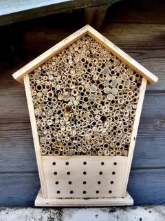 A small house made of wood with lots of bamboo and straw fillings to create nesting holes for wild insects.