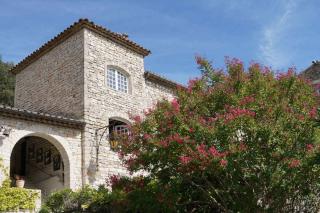 Lagerstroemia, or crepe myrtle, beginning to bloom in front of a ancient stone house