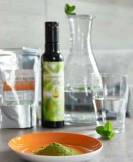 Moringa powder in a dish with bottles and pitchers in the background