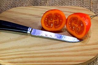 Knife with sliced cyphomandra on a wooden plank